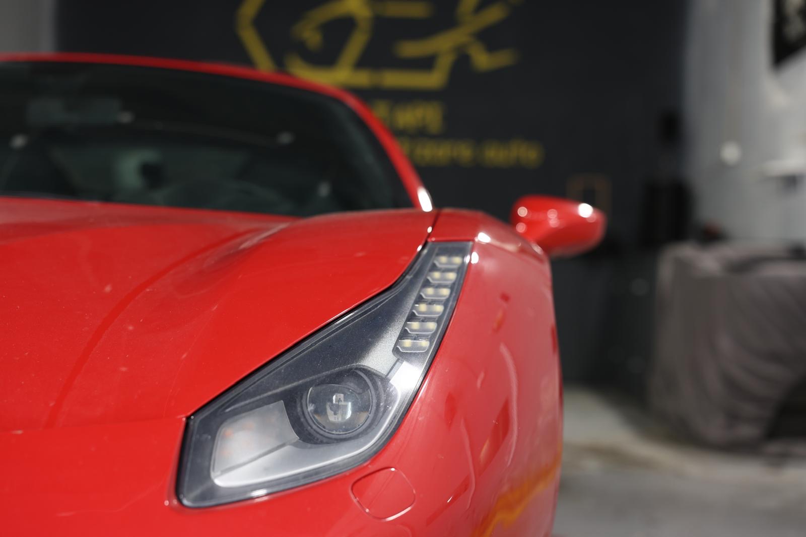 Farul și partea frontală ale unui Ferrari roșu în atelier